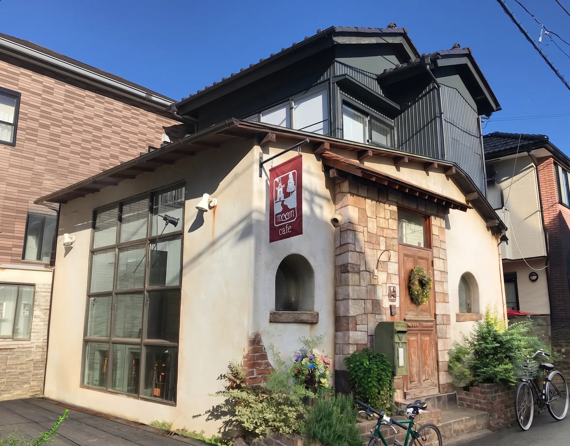 会場のmoom cafe。漆喰の白い壁と石張り、木の扉が印象的な外観