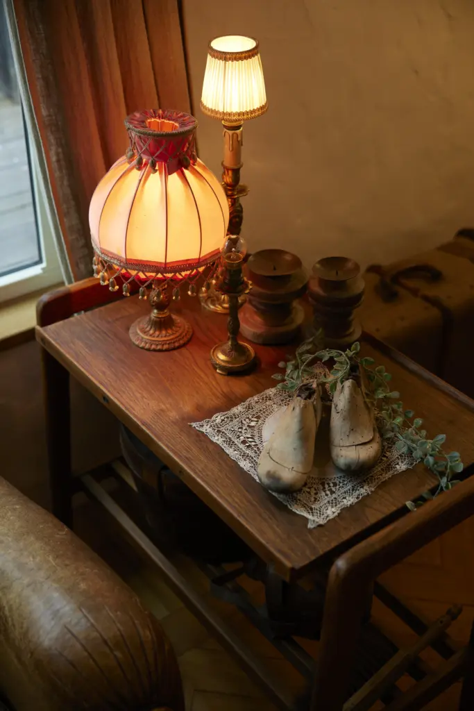 フリンジ付きのアンティークランプや木製のシューキーパーがセンス良く飾られた、アンティクのモデルハウスのサイドテーブル。温かみのある柔らかな灯りがリラックスできる空間を演出している