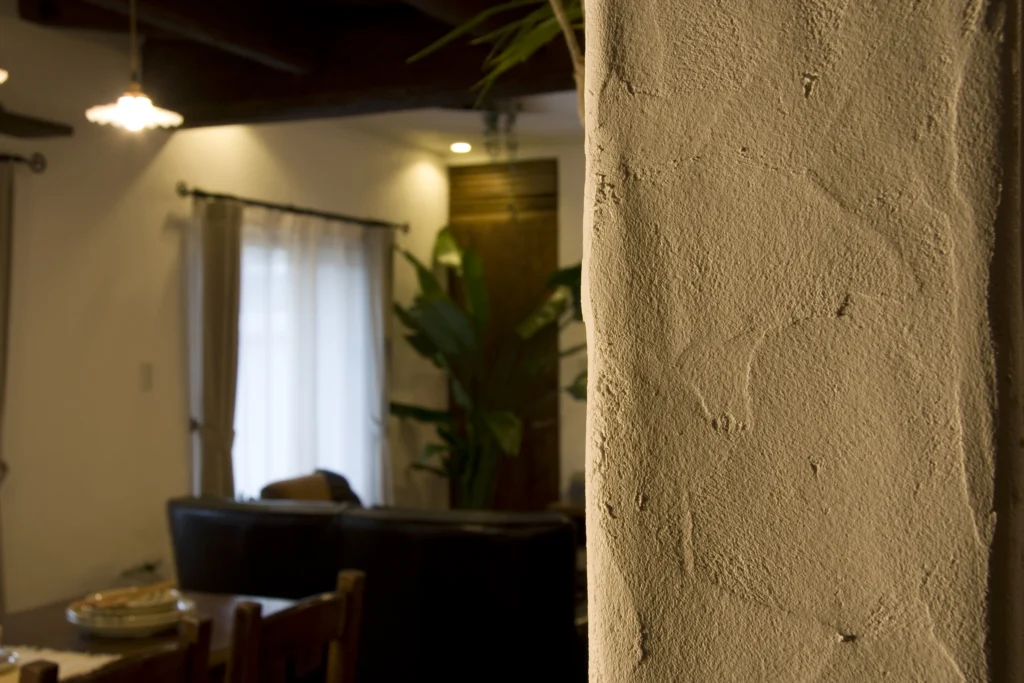 手作業の美しいコテ跡が残る漆喰調の塗り壁と、その奥に広がるリビングダイニング。アンティクのA邸の、自然素材の温もりとアンティーク家具が調和した心地よい空間